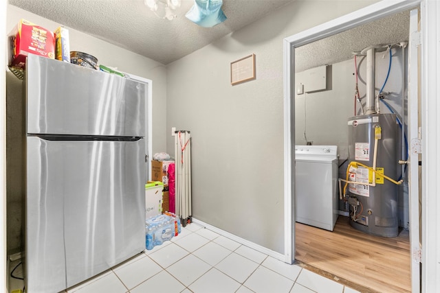 kitchen featuring a textured ceiling, gas water heater, hardwood / wood-style floors, washer / dryer, and stainless steel refrigerator