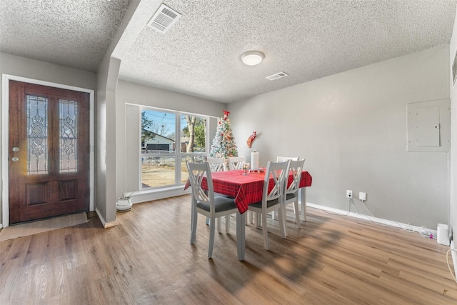 dining room featuring electric panel, wood-type flooring, and a textured ceiling