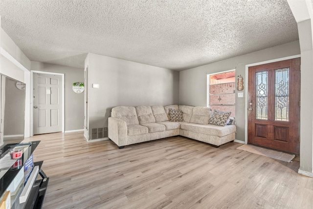 living room featuring a textured ceiling and light wood-type flooring