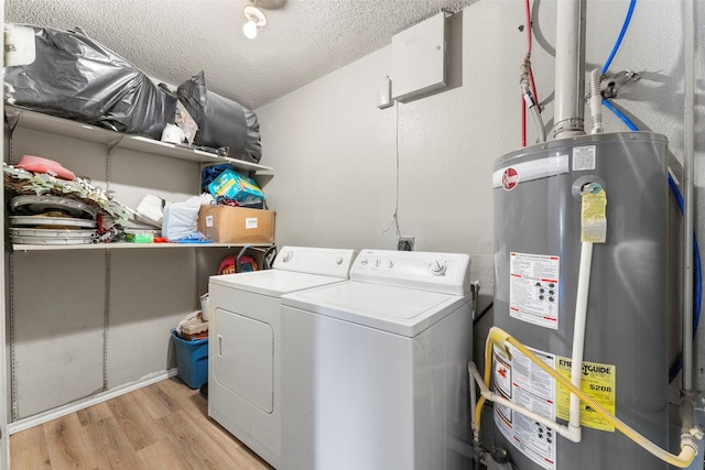 washroom featuring washing machine and clothes dryer, a textured ceiling, light hardwood / wood-style floors, and gas water heater