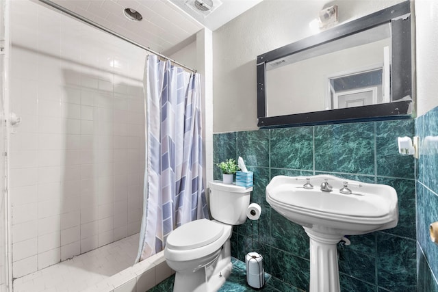 bathroom featuring a shower with shower curtain, toilet, and tile walls