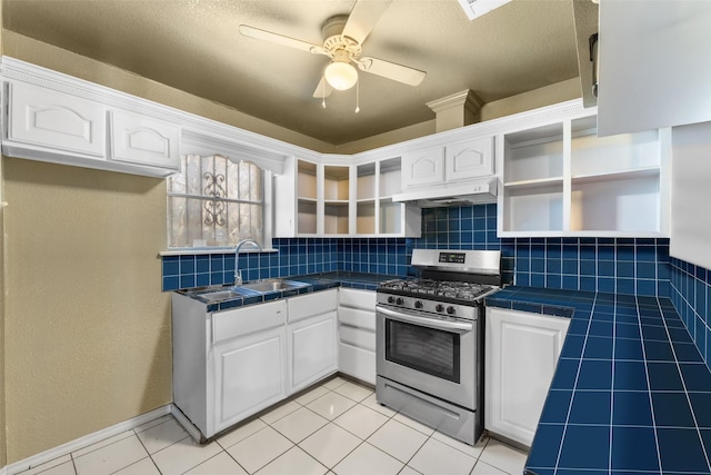 kitchen with tile countertops, white cabinets, sink, stainless steel gas range, and tasteful backsplash