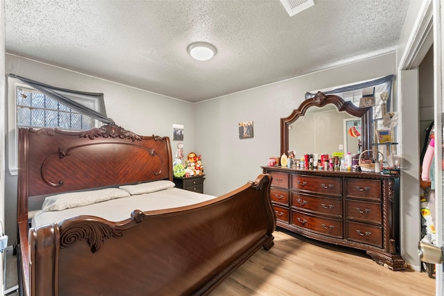 bedroom with a textured ceiling and light wood-type flooring