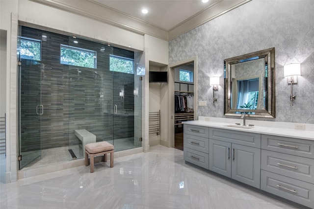 bathroom featuring a healthy amount of sunlight, vanity, a shower with shower door, and ornamental molding