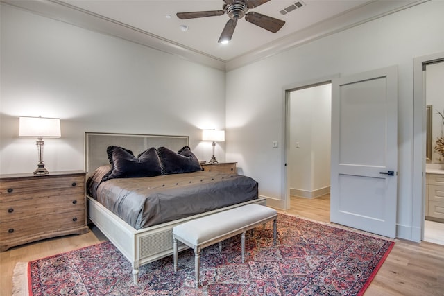 bedroom featuring light wood-type flooring, ensuite bath, ceiling fan, and ornamental molding