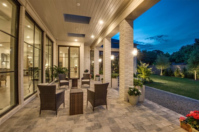 patio terrace at dusk with an outdoor living space and a yard