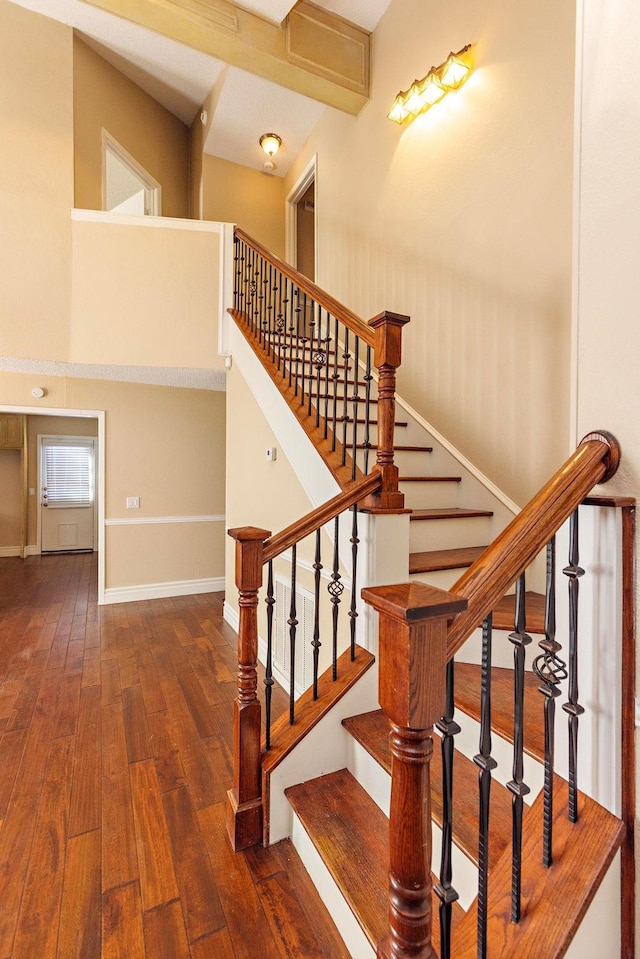 stairway featuring beam ceiling and wood-type flooring