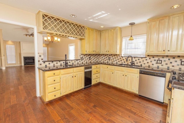 kitchen featuring sink, backsplash, stainless steel dishwasher, and decorative light fixtures