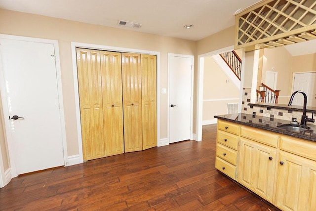 kitchen with light brown cabinets, sink, backsplash, dark wood-type flooring, and dark stone countertops