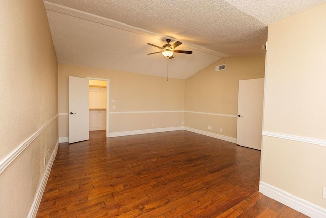 empty room with ceiling fan, dark hardwood / wood-style flooring, vaulted ceiling, and a textured ceiling