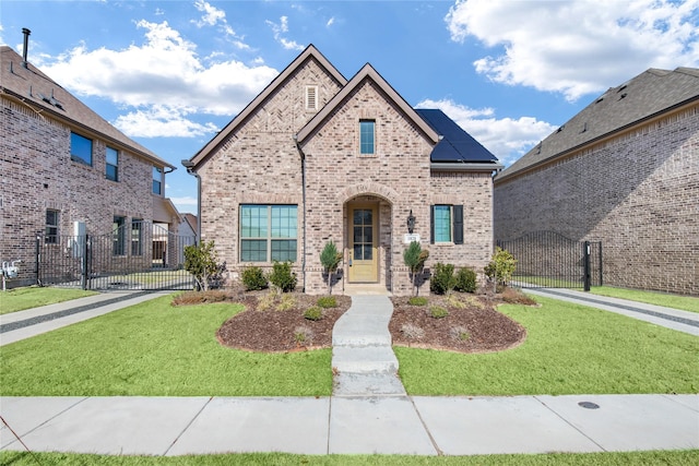 view of front of property with solar panels and a front lawn