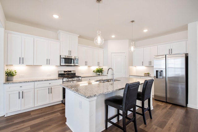 kitchen with appliances with stainless steel finishes, sink, white cabinets, and decorative light fixtures