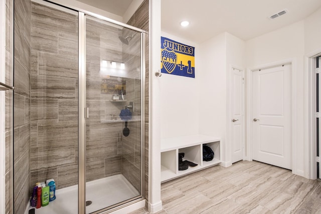 bathroom with a shower with door and wood-type flooring