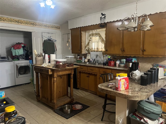 kitchen featuring sink, a breakfast bar area, a center island, washer and dryer, and decorative light fixtures