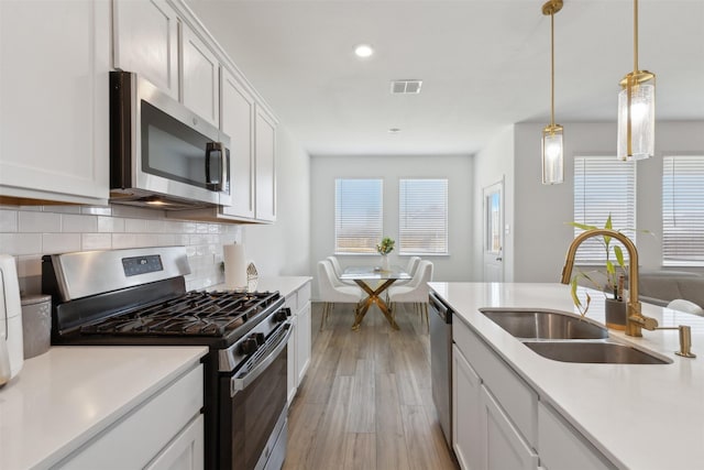 kitchen featuring white cabinetry, sink, light hardwood / wood-style floors, and appliances with stainless steel finishes