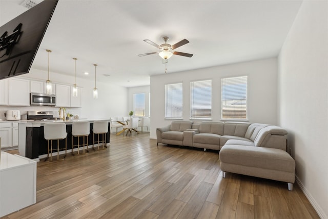 living room featuring sink, light hardwood / wood-style flooring, and ceiling fan