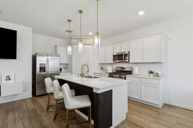 kitchen with white cabinets, stainless steel appliances, hanging light fixtures, and sink