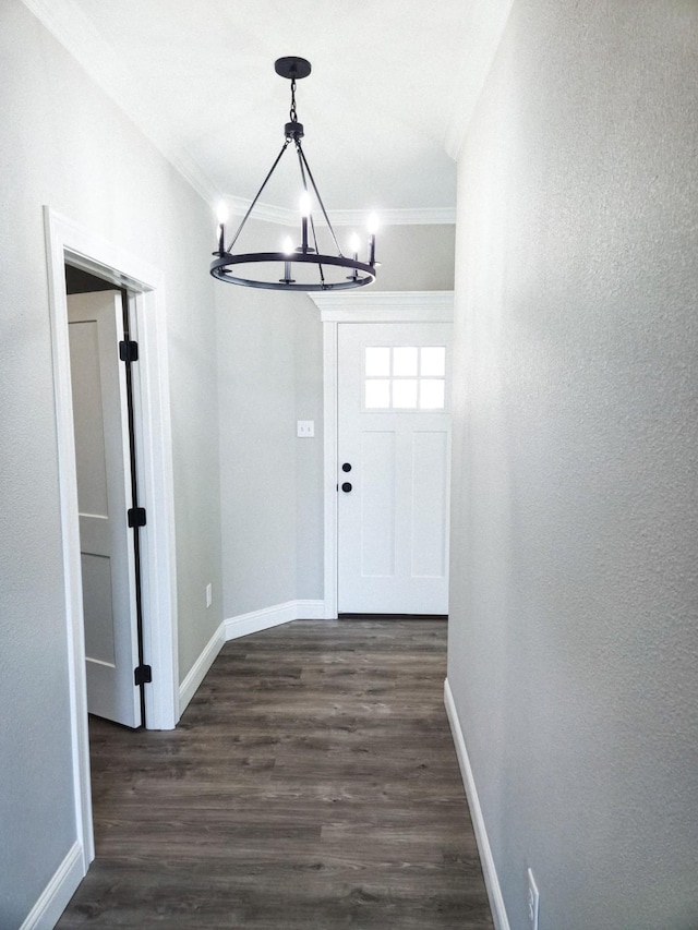 interior space with a chandelier, ornamental molding, dark wood-type flooring, and baseboards