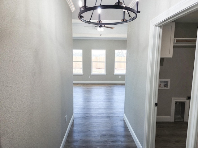 corridor featuring baseboards, a textured wall, dark wood finished floors, and a notable chandelier