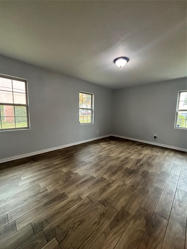 spare room featuring dark hardwood / wood-style flooring and a wealth of natural light