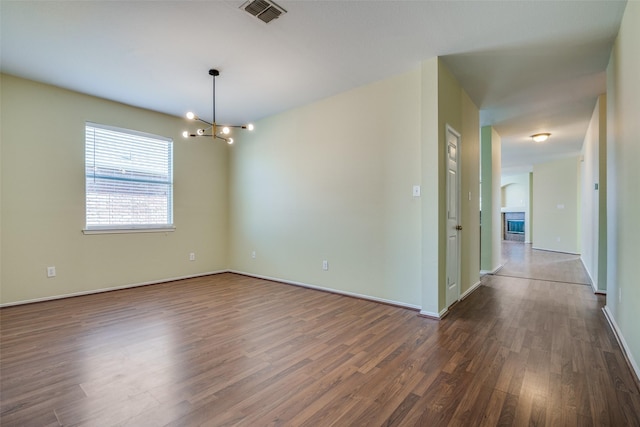 empty room with an inviting chandelier and dark hardwood / wood-style flooring