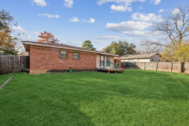 rear view of property featuring a lawn and a deck