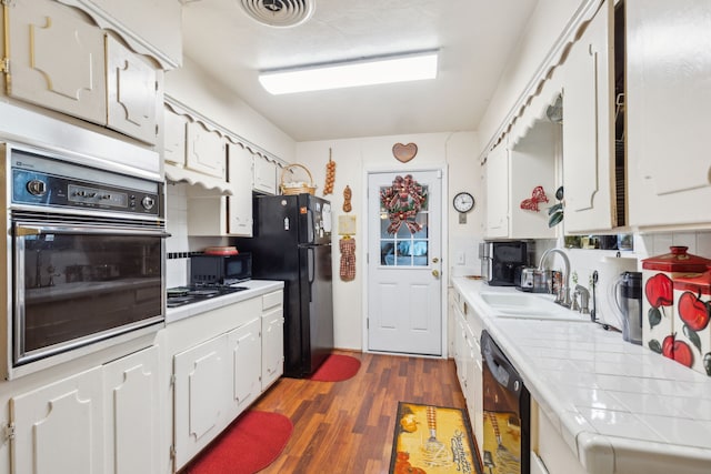 kitchen with tile countertops, black appliances, white cabinets, sink, and dark hardwood / wood-style flooring