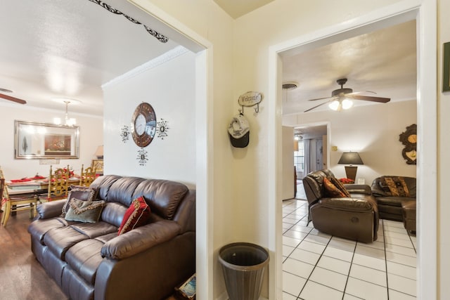 tiled living room featuring ceiling fan with notable chandelier and ornamental molding