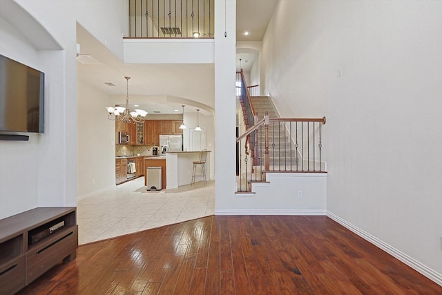 living area featuring light wood finished floors, baseboards, arched walkways, stairs, and a chandelier