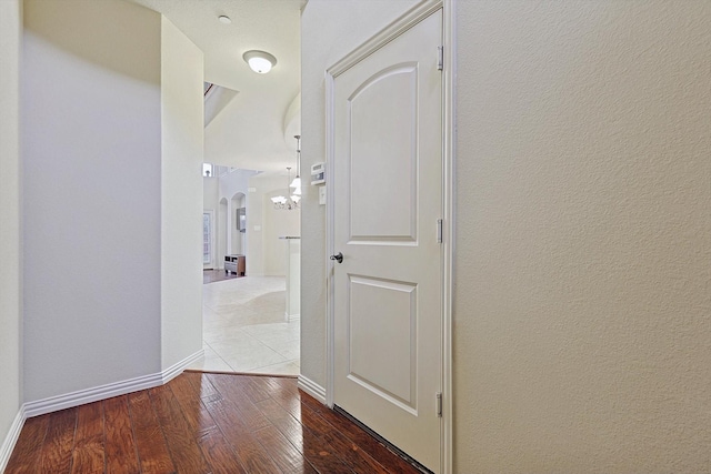 hall featuring arched walkways, wood-type flooring, and baseboards