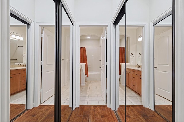 corridor with light wood finished floors and a sink