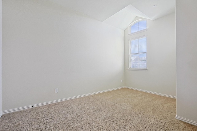 unfurnished room with light carpet, baseboards, and vaulted ceiling