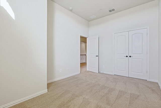 unfurnished bedroom featuring arched walkways, carpet floors, visible vents, baseboards, and a closet