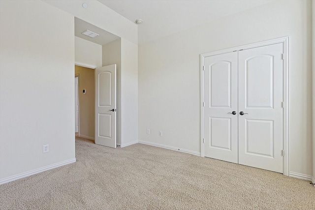 unfurnished bedroom with light colored carpet and a closet