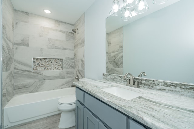 full bathroom featuring tiled shower / bath, hardwood / wood-style floors, vanity, and toilet