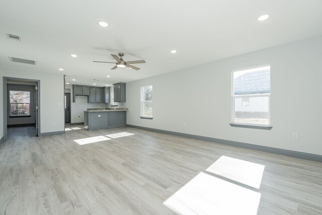 unfurnished living room with ceiling fan, light hardwood / wood-style floors, and a wealth of natural light