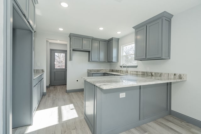 kitchen with sink, gray cabinets, kitchen peninsula, and light hardwood / wood-style floors