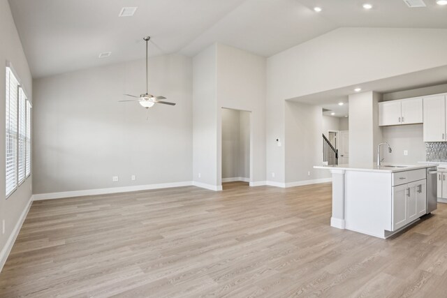 kitchen with a center island with sink, light hardwood / wood-style floors, sink, and high vaulted ceiling