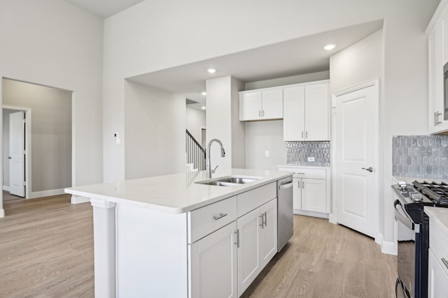 kitchen with a kitchen island with sink, sink, white cabinets, and stainless steel appliances