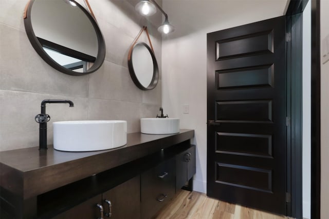 bathroom featuring vanity, wood-type flooring, and tile walls