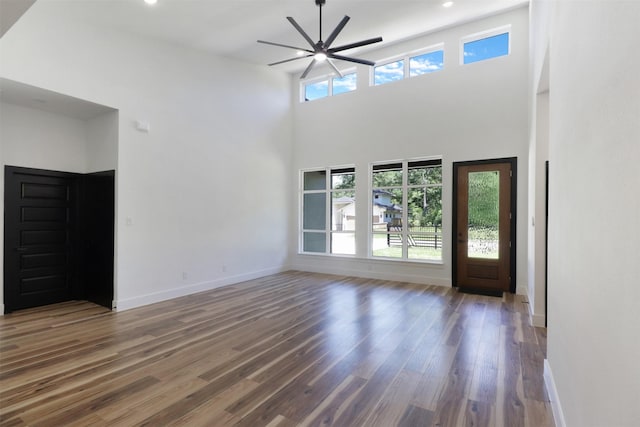 unfurnished living room featuring dark hardwood / wood-style flooring, plenty of natural light, and a towering ceiling