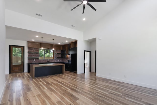 kitchen featuring a center island, high vaulted ceiling, ceiling fan, light hardwood / wood-style floors, and dark brown cabinetry