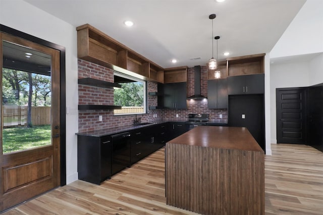 kitchen featuring wall chimney exhaust hood, a center island, light wood-type flooring, pendant lighting, and black appliances