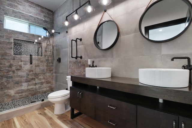 bathroom featuring tasteful backsplash, an enclosed shower, vanity, tile walls, and hardwood / wood-style flooring