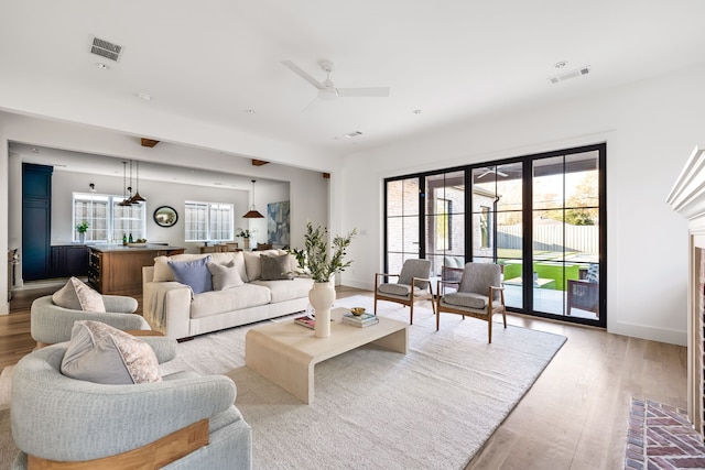 living room featuring ceiling fan, light wood-type flooring, and a wealth of natural light