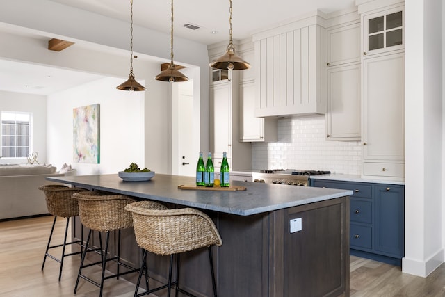 kitchen with decorative light fixtures, white cabinetry, blue cabinets, and light hardwood / wood-style flooring