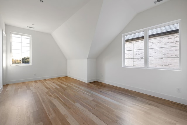 additional living space featuring vaulted ceiling and light wood-type flooring