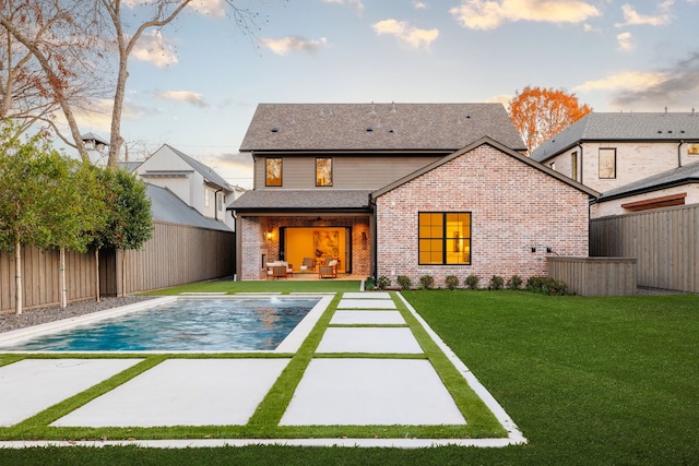 rear view of house with a fenced in pool, a patio area, and a yard