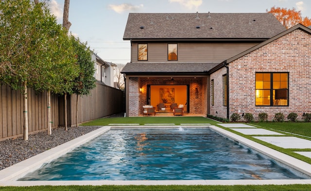 back of house with outdoor lounge area, a patio area, a fenced in pool, and a yard