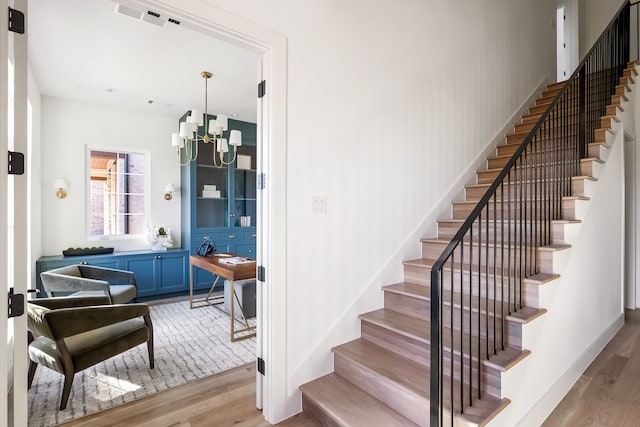 staircase with a chandelier and hardwood / wood-style flooring